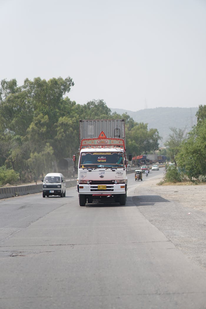 Vibrantly decorated truck traveling on a scenic highway in Pakistan.